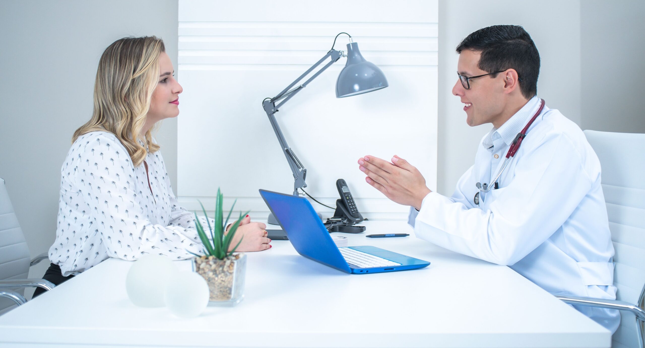 A doctor conducts a patient consultation in a bright, modern medical office.